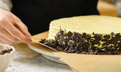 Hand trägt Zuckerstreusel an den Tortenrand auf