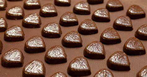 Handarbeit beim Verzieren von Pralinen in der Confiserie