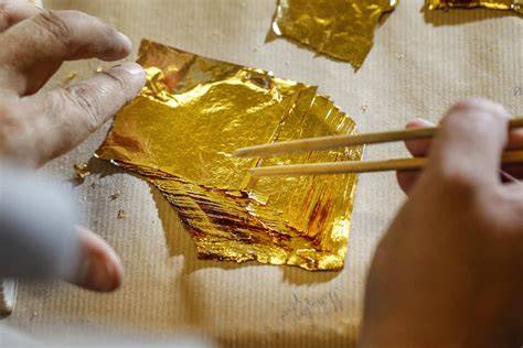 Handwerkliche Herstellung von Honig mit Blattgold: Goldblättchen werden in ein Honigglas gelegt