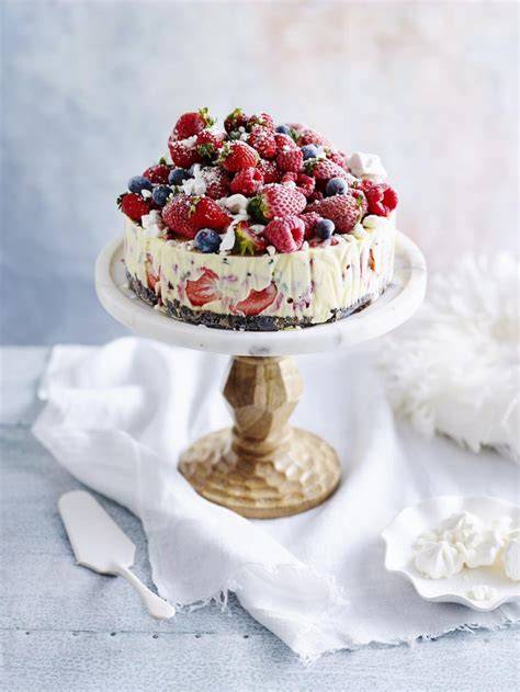 Hausgemachte Eistorte mit Beeren und Keksboden, aufgeschnitten auf sommerlich gedecktem Tisch