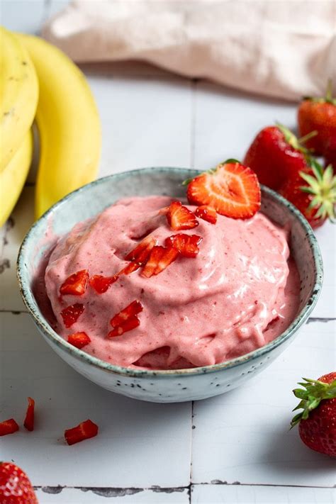 Hausgemachtes Erdbeereis ohne Zucker in einer Schale, garniert mit frischen Erdbeeren und Minze