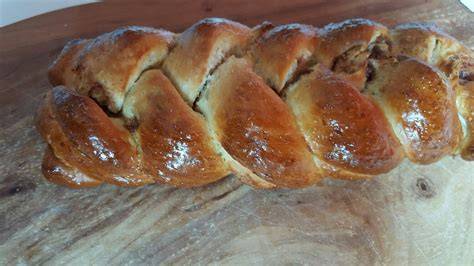 Hefezopf, frisch gebacken, auf Backpapier, daneben Schälchen mit Zimt und Zucker