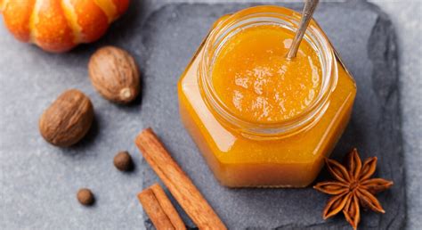 Herbstliche Kürbis-Orangen-Marmelade im Glas neben frischen Orangen und Hokkaido