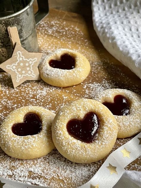 Herzplätzchen mit Marzipan und rubinroter Himbeerfüllung auf einem Gitter