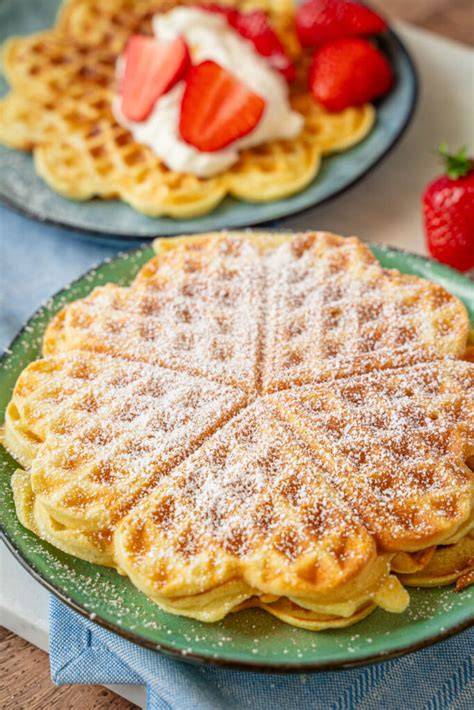 Herzwaffeln auf Gitter mit Puderzucker und Kirschen