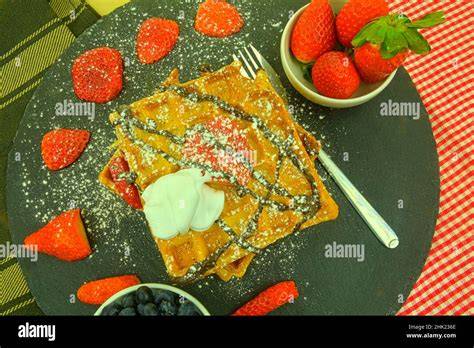 Herzwaffeln auf einem Teller mit Puderzucker und Beeren
