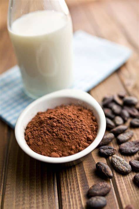 Hitzetopf mit Milch und Kakaopulver, Gewürze daneben