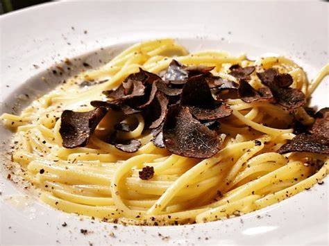 Hobeln von schwarzem Trüffel über Pasta