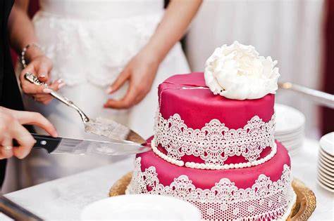 Hochzeitstorte mit Brautpaar beim Anschneiden