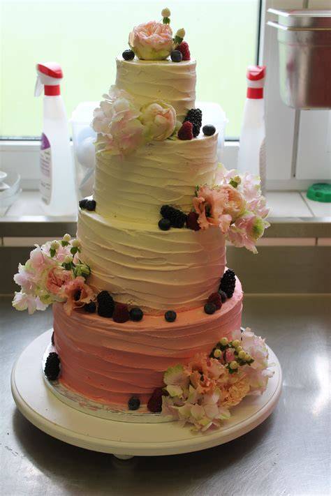 Hochzeitstorte mit essbaren Blüten und frischen Früchten