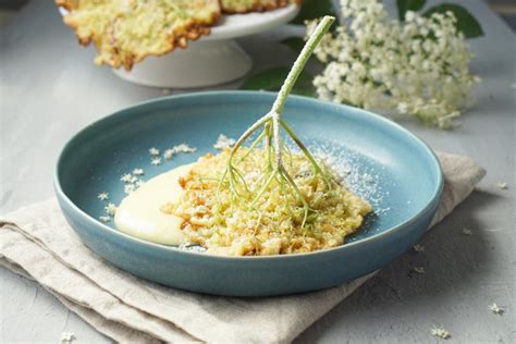 Holunderblütendolden und ein Stück Holunderblüten-Quark-Torte auf einer Tortenplatte