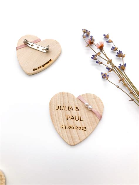 Holz- und Filz-Lebkuchenherz-Anstecker nebeneinander, Nahaufnahme der Gravur und des Drucks