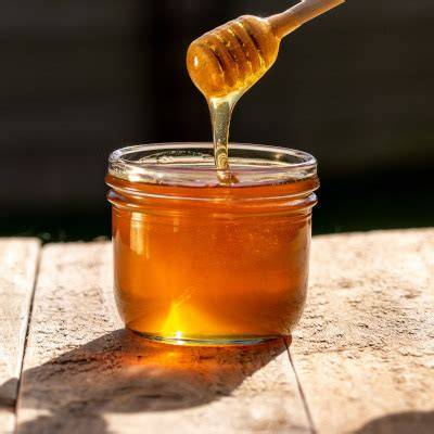 Honig im Glas mit Bienenstock im Hintergrund