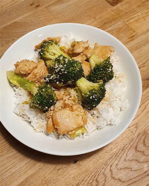 Honig-Sesam-Hähnchen mit Brokkoli im Wok, glänzende Sauce, angerichtet neben Basmatireis