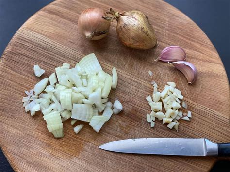 Honigglas mit Löffel, daneben frische Zwiebeln und Knoblauch