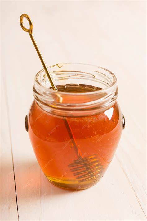 Honiglöffel über Glas mit flüssigem Honig