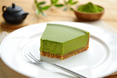 Japanischer Matcha Cheesecake auf weißem Teller mit Matchapulver und geröstetem Sesam bestreut