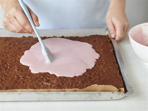 Joghurt-Guss wird mit einem Pinsel auf heißem Kuchen verteilt