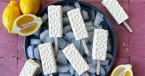 Joghurt-Zitronen Eis am Stiel auf einem Teller mit Zitronenscheiben