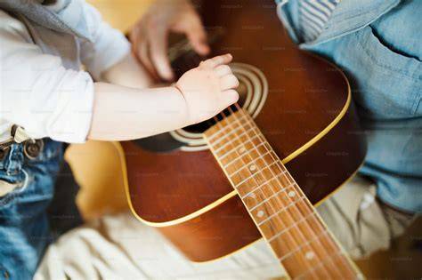 Junge übt Gitarre mit Vater