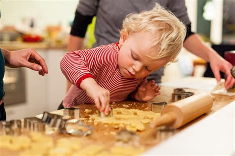 Junge Familie sticht gemeinsame Plätzchen aus - Ausstecherformen und Backen mit Kindern