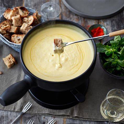 Käsefondue angerichtet im Caquelon mit Trüffelscheiben