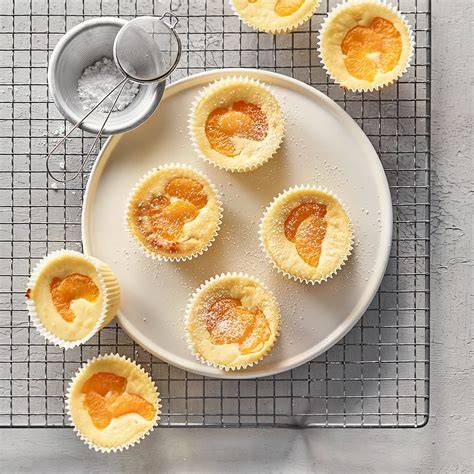 Käsekuchen Muffins auf einem Tisch mit Tee und Früchten zur Deko