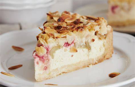 Käsekuchen angerichtet mit Sommerfrüchten, Honig und gerösteten Mandeln