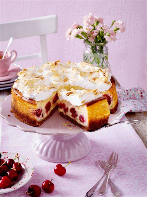 Käsekuchen mit Kirschen und Baiser auf Tortenplatte