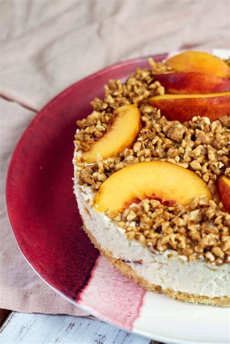 Käsekuchen mit Nektarinen vor sommerlicher Kulisse, angeschnitten