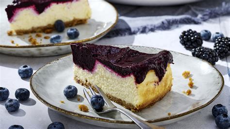 Käsekuchen mit Waldbeeren auf rustikalem Holztisch, Detail vom Beerenmix