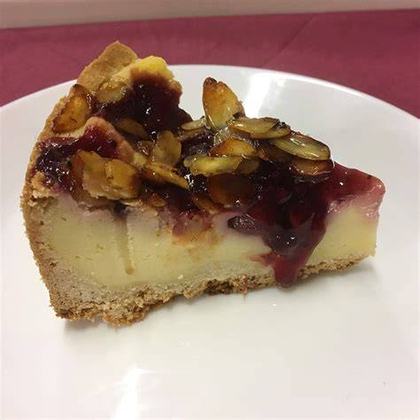 Käsekuchen mit roter Grütze und Mandelhaube auf Kaffeetafel
