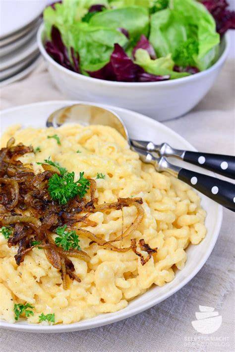 Käsekuchen und schwäbische Käsespätzle nebeneinander aufgedeckt