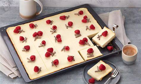 Käsekuchen vom Blech, frisch gebacken mit Himbeeren und Schokolade dekoriert