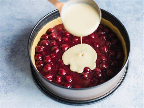Käsekuchenmasse mit eingearbeiteten Kirschen in der Springform