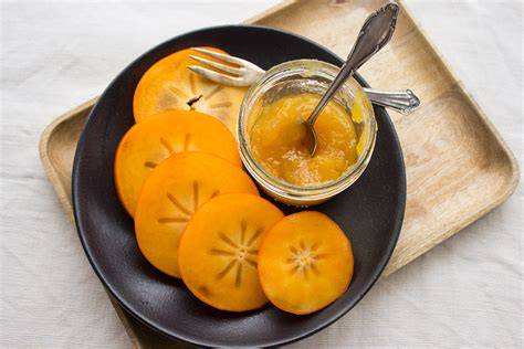 Kaki Marmelade im Glas auf Frühstückstisch
