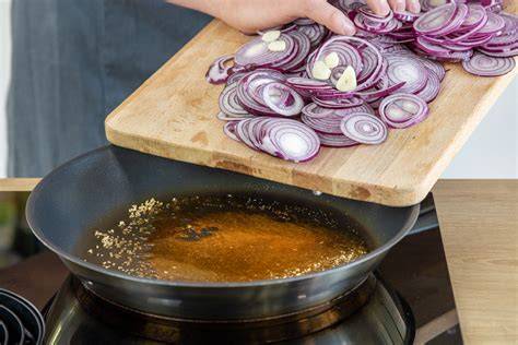 Karamellisierte Zwiebelringe mit goldbraunem Glanz in der Pfanne