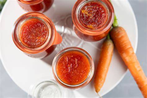 Karotten Ingwer Marmelade auf Brot, umgeben von frischen Karotten und Ingwer