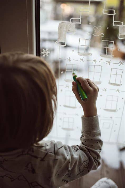 Kind malt mit Coppenrath Kreidemarker ein Fensterbild