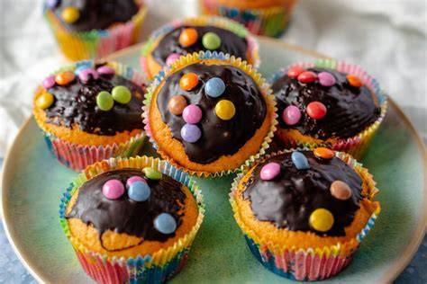 Kinder, die Mini-Kuchen und Muffins mit Freude verzieren