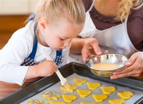 Kinder backen Plätzchen in der Weihnachtsbäckerei, Ausstechformen und bunte Streusel