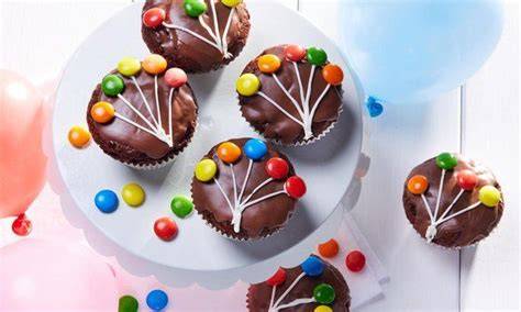 Kinder dekorieren gemeinsam Schokomuffins für einen Geburtstag