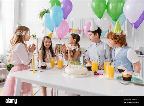 Kinder singen Happy Birthday mit Kuchen und Kerzen