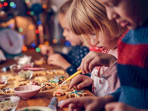 Kinder verzieren bunte Kekse gemeinsam am Tisch