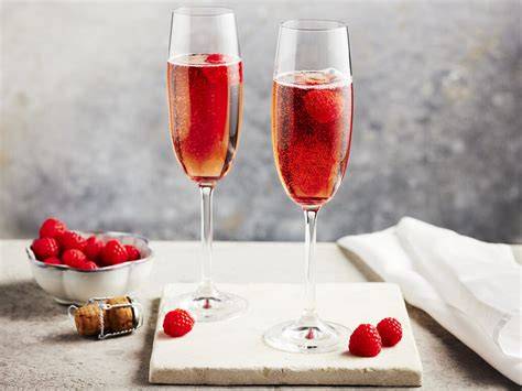 Kir Royal Trüffel auf weißem Teller mit frischen Johannisbeeren und einem Glas Kir Royal