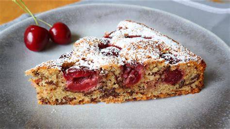 Kirsch-Nuss-Kuchen, angeschnittenes Stück mit Kirschen und Schokoraspeln