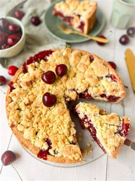 Kirschkuchen mit Streusel angeschnitten auf rustikaler Holzplatte