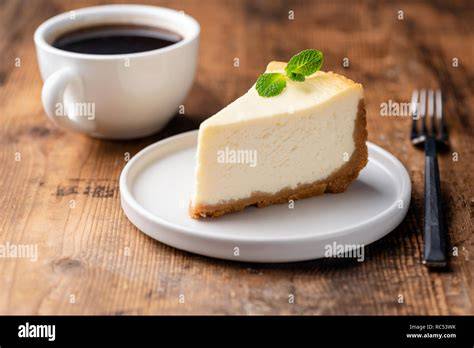 Klassischer Käsekuchen, angeschnitten, auf rustikalem Holztisch, mit Kaffee