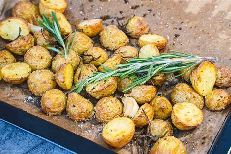 Knoblauch, Thymian und Rosmarin neben bräunenden Kartoffeln