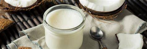Kokosöl im Glas, Löffel Honig und Kokosnuss auf Naturhintergrund